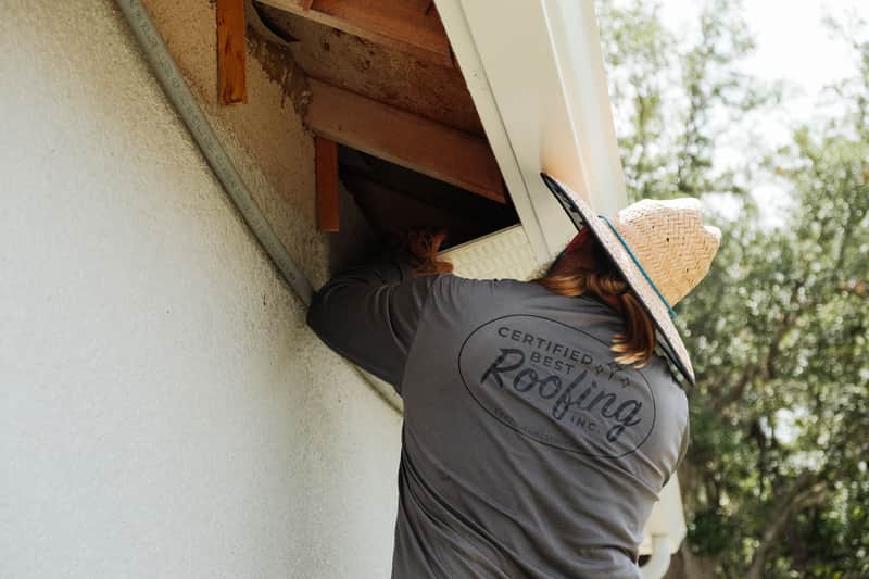 Certified Best Roofing crew member repairing damaged soffit and sub-fascia on a stucco home