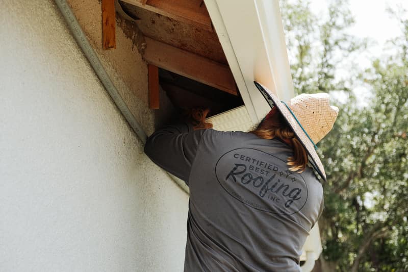 Certified Best Roofing crew member repairing damaged soffit and sub-fascia on a stucco home