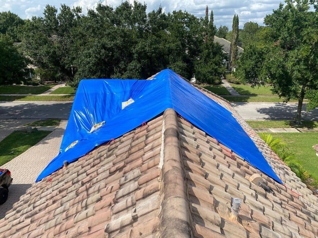Blue emergency tarp secured over a storm-damaged tile roof in a Central Florida neighborhood