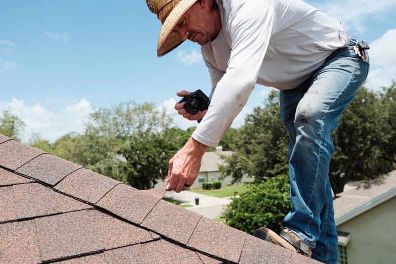 Certified roof inspector examining shingles with a clipboard on a Florida roof